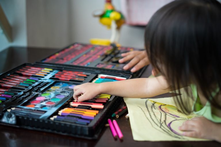 Toddler choosing colours while drawing on a paper at home.